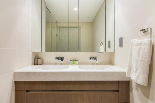 a bathroom with two sinks and a large mirror at Luxe Living in Beachfront / 2BR in Dubai Marina in Dubai