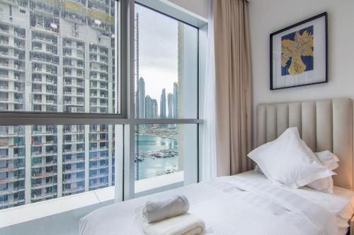 a bedroom with a bed and a large window at Luxe Living in Beachfront / 2BR in Dubai Marina in Dubai