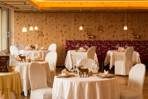 un comedor con mesas blancas y sillas blancas en Hotel Emmy - five elements en Fiè