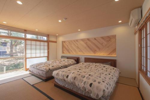 a bedroom with two beds and a large window at Private hot-spring Villa in Kusatsu in Kusatsu