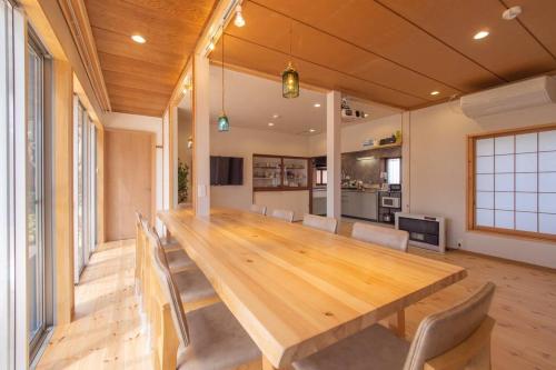 a large wooden table in a room with chairs at Private hot-spring Villa in Kusatsu in Kusatsu