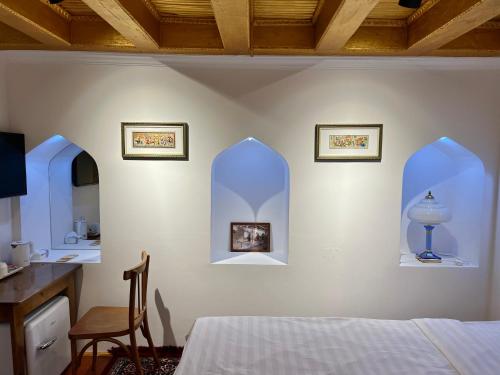 a bedroom with a bed and a desk and two windows at Usman Heritage Hotel in Bukhara