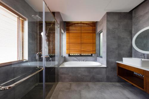 uma casa de banho com uma banheira, um chuveiro e um lavatório. em Villa 4PN l RESORT BIỂN HỒ TRÀM l view biển l BAO GỒM ĂN SÁNG em Xuyên Mộc