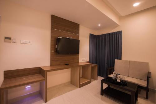 a room with a television and a desk with a table at SMA Grand inn, Triplicane in Chennai