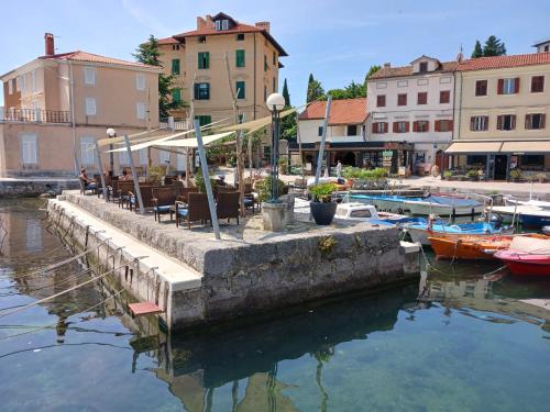 a marina with tables and chairs and boats in the water at Apartment Lady Daniela mit Meerblick in Lovran in Lovran