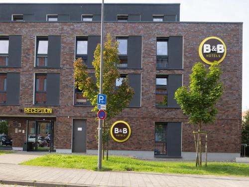 un bâtiment en briques avec deux panneaux de stationnement devant lui dans l'établissement B&B Hotel Kiel-Wissenschaftspark, à Kiel