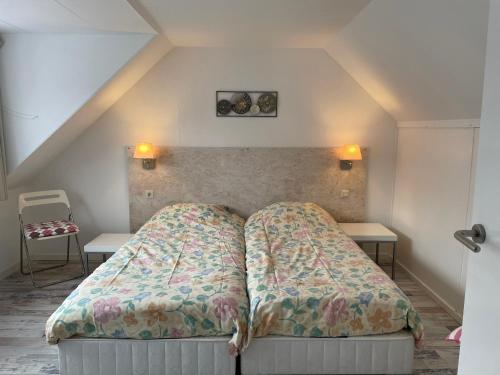 Bett in einem kleinen Zimmer mit 2 Tischen in der Unterkunft De Linden in Egmond aan Zee