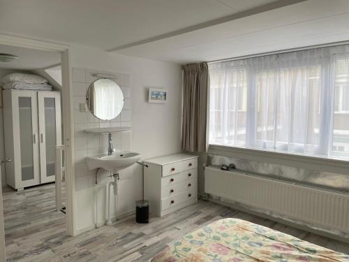 een badkamer met een wastafel, een bad en een raam bij De Linden in Egmond aan Zee