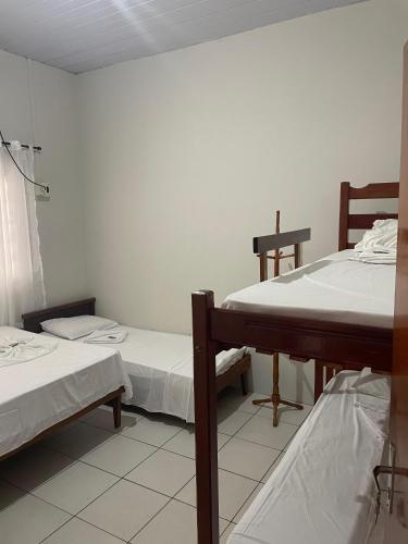 a room with two beds and a table in it at Pousada Ambiente Familiar in Ponte Alta do Tocantins
