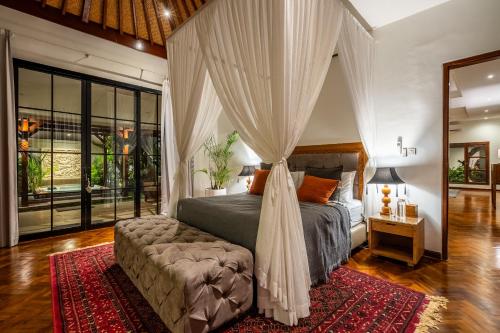 ein Schlafzimmer mit einem Himmelbett und einem Sofa in der Unterkunft Tranquility Manor Bali in Sanur