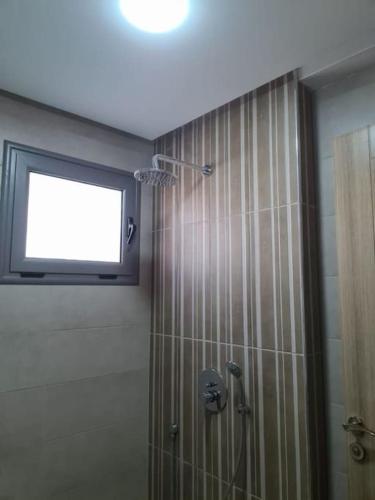 La salle de bains est pourvue d'une douche et d'une télévision murale. dans l'établissement Apt S+2 Centre ville Gabès, à Gabès