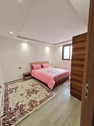 - une chambre avec un lit doté d'oreillers roses et d'un tapis dans l'établissement Apt S+2 Centre ville Gabès, à Gabès