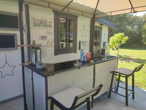 une cuisine extérieure avec un bar et un tabouret dans l'établissement Camping sous les belles etoiles, à Peyrilhac