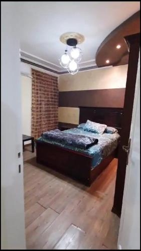 Schlafzimmer mit einem Bett und Holzboden in der Unterkunft شقة مفروشة فاخرة بأرقى مواقع المنصورة in Mît Khamîs