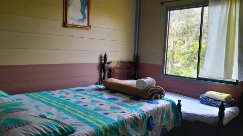 1 dormitorio con 1 cama en una habitación con ventana en Cabaña La Guitarra, en Betania