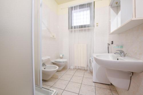 a white bathroom with a sink and a toilet at Residence Parco in Sirmione