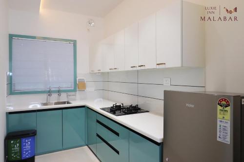 a kitchen with blue and white cabinets and a refrigerator at LUXIE INN MALABAR in Perintalmanna