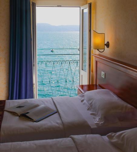 a bedroom with a bed with a view of the ocean at Hotel Garnì Riviera in Gargnano