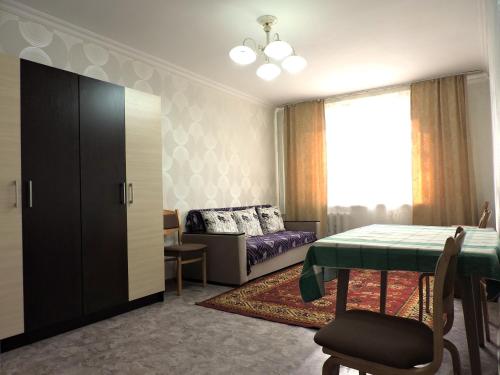a bedroom with a bed and a table and a couch at NBG Flat in Almaty