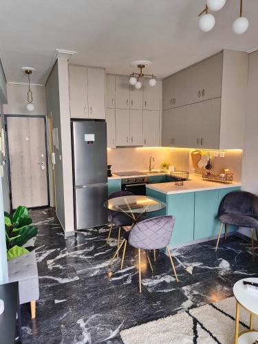 uma cozinha com frigorífico, mesas e cadeiras em Olivia Apartment-Private parking em Chalkida