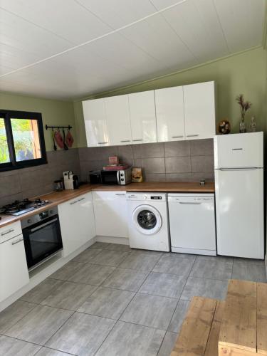 a kitchen with white cabinets and a washing machine at Chalet nature proche plage in La Ciotat