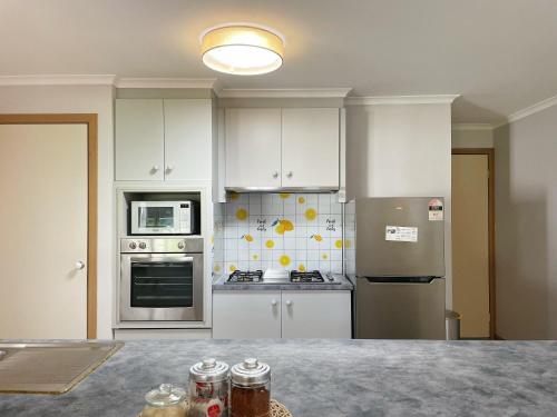 una cocina con armarios blancos y electrodomésticos de acero inoxidable en YF Hostel, en Craigieburn