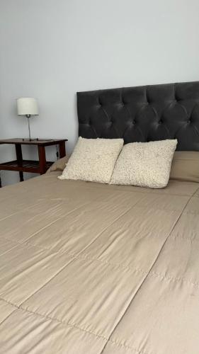 łóżko z czarnym zagłówkiem i dwoma poduszkami w obiekcie Premium apart nueva cordoba w Córdobie