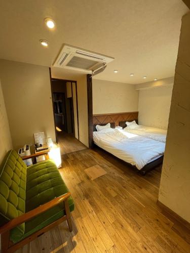 a bedroom with two beds and a green couch at etoile inn sumoto - Vacation STAY 49252v in Sumoto