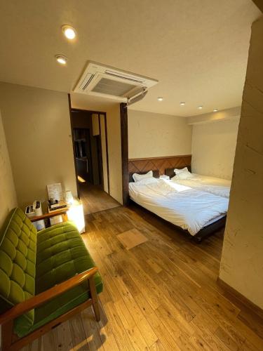 - une chambre avec 2 lits et un canapé vert dans l'établissement etoile inn sumoto - Vacation STAY 49252v, à Sumoto