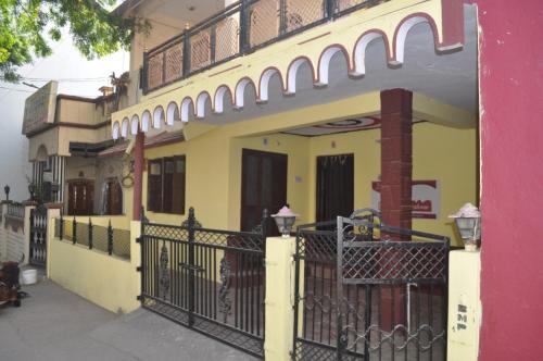 un edificio amarillo y rosa con una valla negra en Virndawan House en Maheshwar