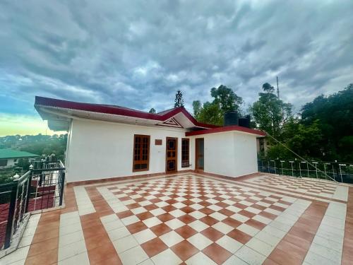 een klein wit huis met een rood dak bij Snow Biscuit Villa in Dharamshala