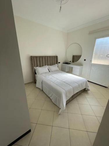 ein weißes Schlafzimmer mit einem Bett und einem Spiegel in der Unterkunft Fayb-Sweet-Home-4 - Cité Essalam in Agadir