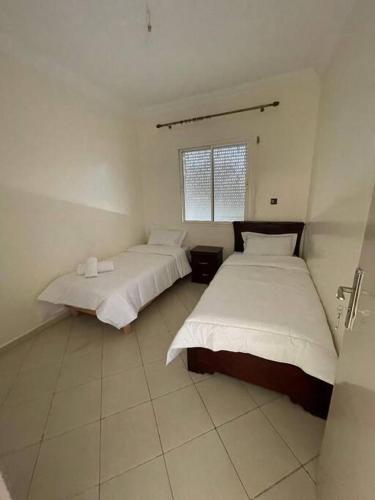 2 Betten in einem Zimmer mit weißen Wänden in der Unterkunft Fayb-Sweet-Home-4 - Cité Essalam in Agadir