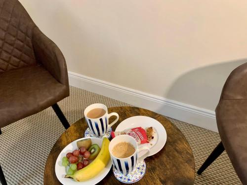 una mesa con dos tazas de café y un plato de fruta en Atlantic View Rooms, en Burtonport