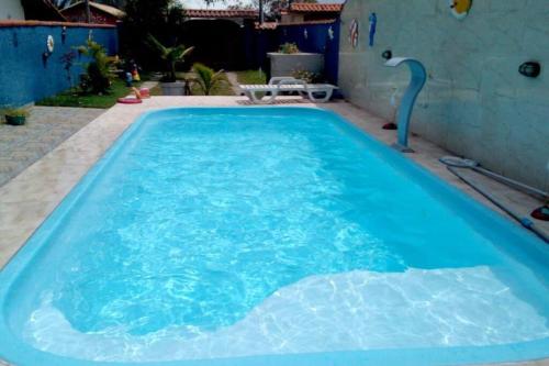 een groot zwembad met blauw water in een achtertuin bij Casa Temporada à Beira da Praia in Maricá