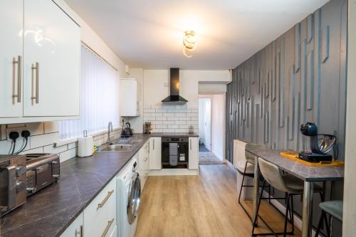 a large kitchen with white cabinets and wooden floors at 5-Bedroom home - Ideal for groups working away from home in Swansea