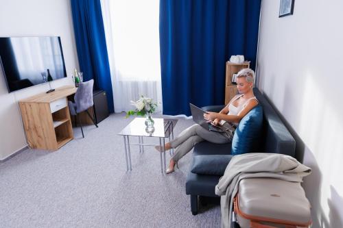 a man sitting in a chair with a laptop at Hotel FIT in Přerov