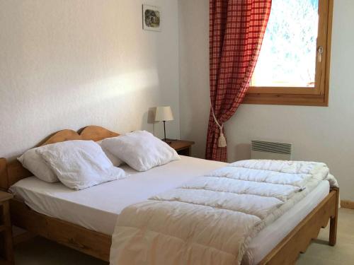 um quarto com uma cama com lençóis brancos e uma janela em Appartement Le Grand-Bornand, 2 pièces, 6 personnes - FR-1-458-197 em Le Grand-Bornand