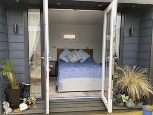 a bedroom with a bed inside of a glass door at Beautiful new Garden Annexe in Ashton in Makerfield