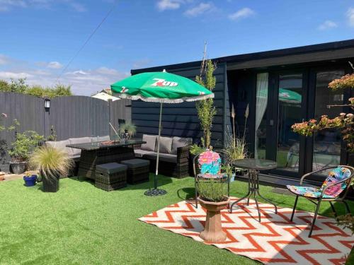 a patio with an umbrella and a table and chairs at Beautiful new Garden Annexe in Ashton in Makerfield