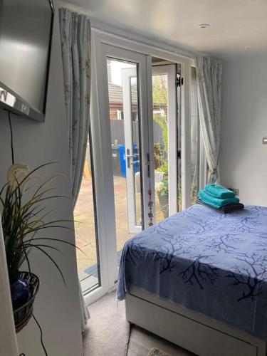 a bedroom with a bed and a sliding glass door at Beautiful new Garden Annexe in Ashton in Makerfield