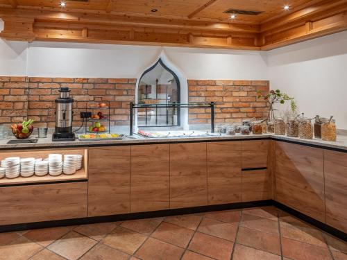 a kitchen with wooden cabinets and a brick wall at Hotel Jagdschlössl in Kirchdorf in Tirol