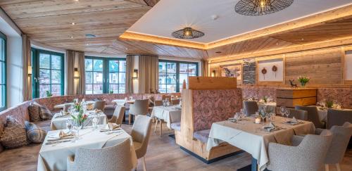 a restaurant with white tables and chairs and windows at Hotel Jagdschlössl in Kirchdorf in Tirol