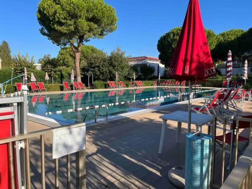 piscina con sedie e ombrellone rosso di Casina mare bibbona a Marina di Bibbona