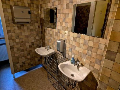 a tiled bathroom with two sinks and a mirror at Vater Bender Heim in Schotten