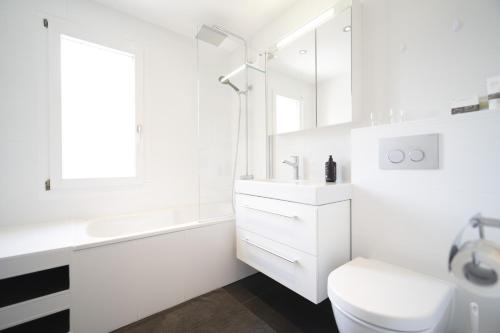 a white bathroom with a sink and a toilet at Chasa Stradun 400 in Scuol