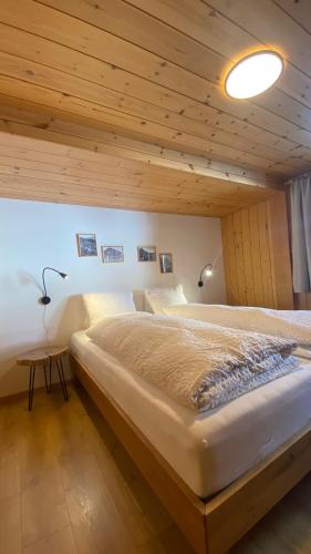 a large bed in a room with a wooden ceiling at Bergquelle 1.OG in Bettmeralp