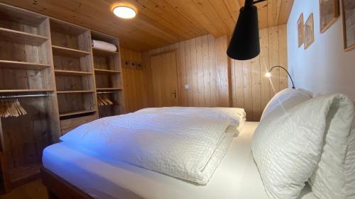 a bedroom with a white bed with wooden walls at Bergquelle 1.OG in Bettmeralp