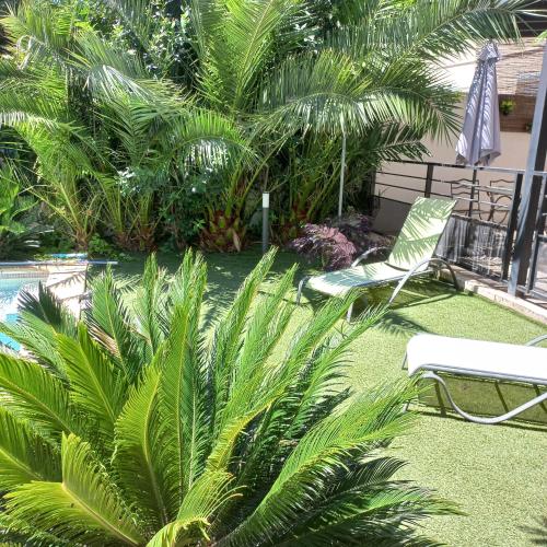 une chaise verte et des palmiers dans une cour dans l'établissement La Secrète d'Avignon, à Avignon