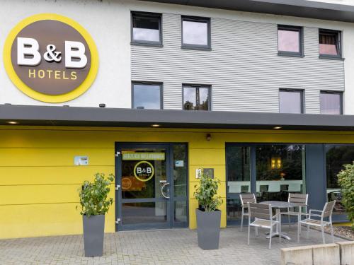 a yellow building with a table and chairs outside at B&B Hotel Koblenz in Koblenz